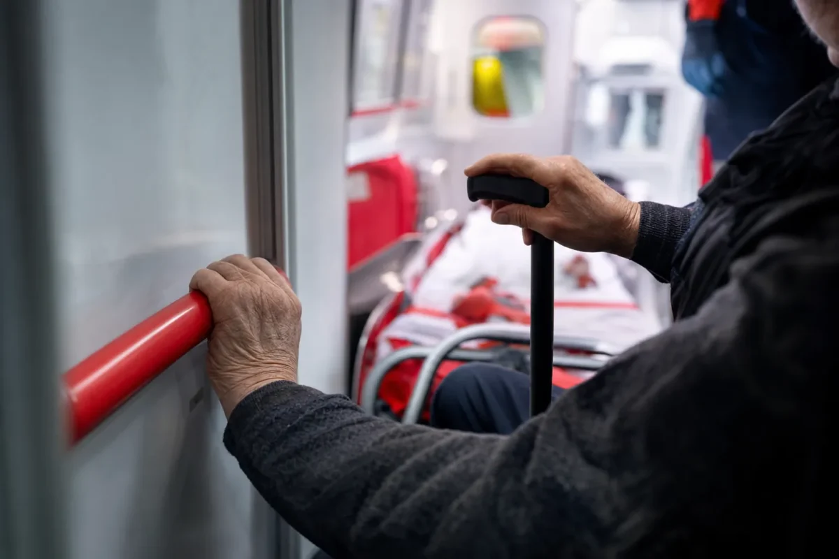 gros plan sur une main agrippant la barre d'appui laterale d'un vehicule, l'autre main posee sur une canne, dans une lumiere