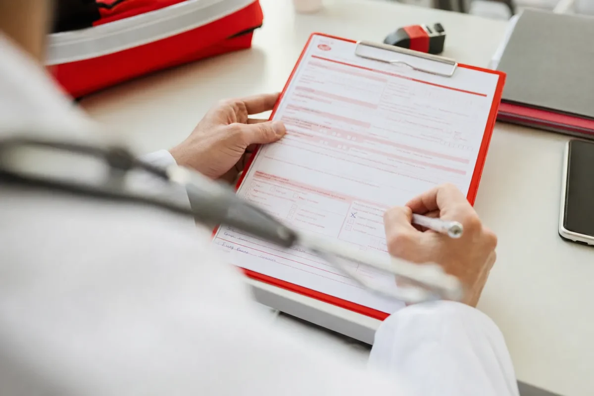 plan serre sur les mains d'un medecin remplissant un formulaire Cerfa avec un stylo, une case de mode de transport cochee