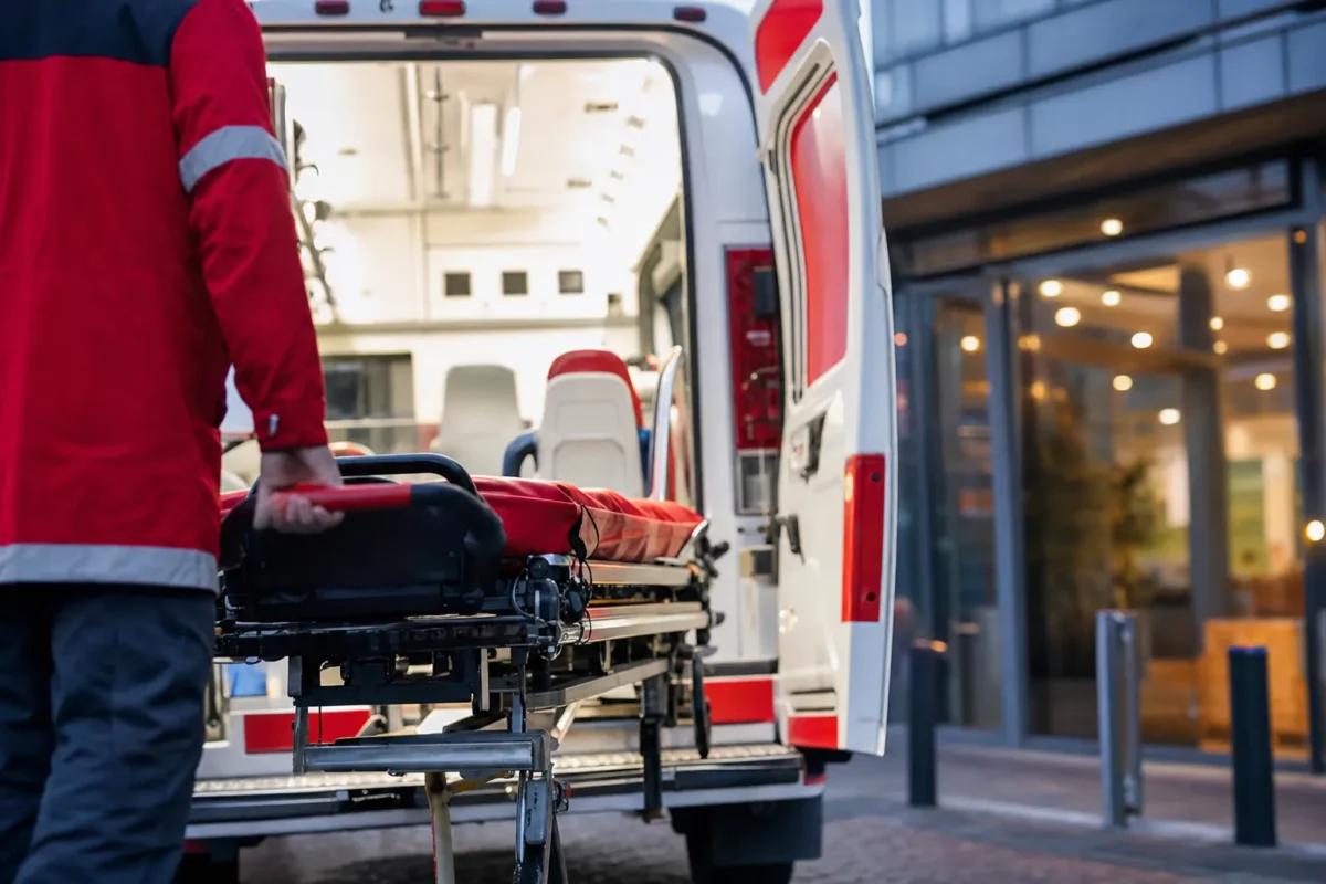 arriere d'une ambulance conventionnee aux portes ouvertes devant l'entree vitree d'un etablissement de soin lyonnais